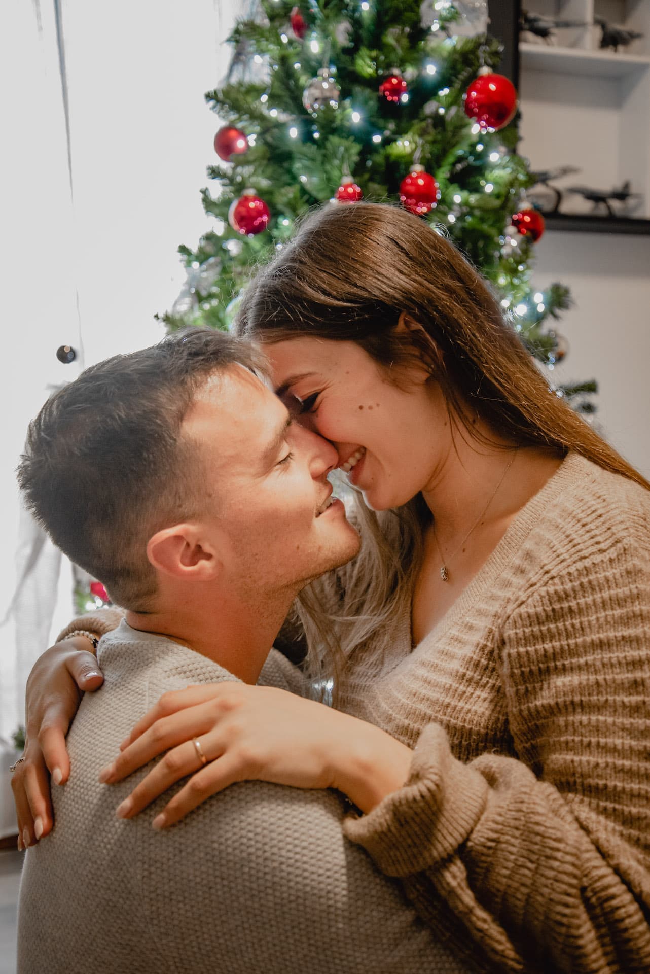 coppia a natale luci palline albero sguardi bacio fronte