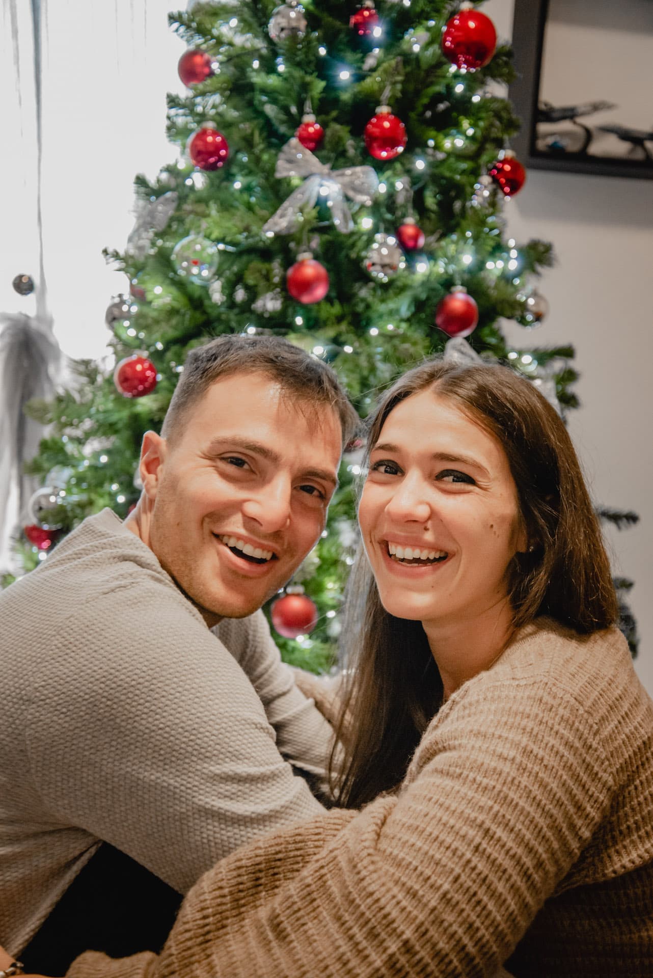 coppia a natale luci palline albero sorrisi abbraccio