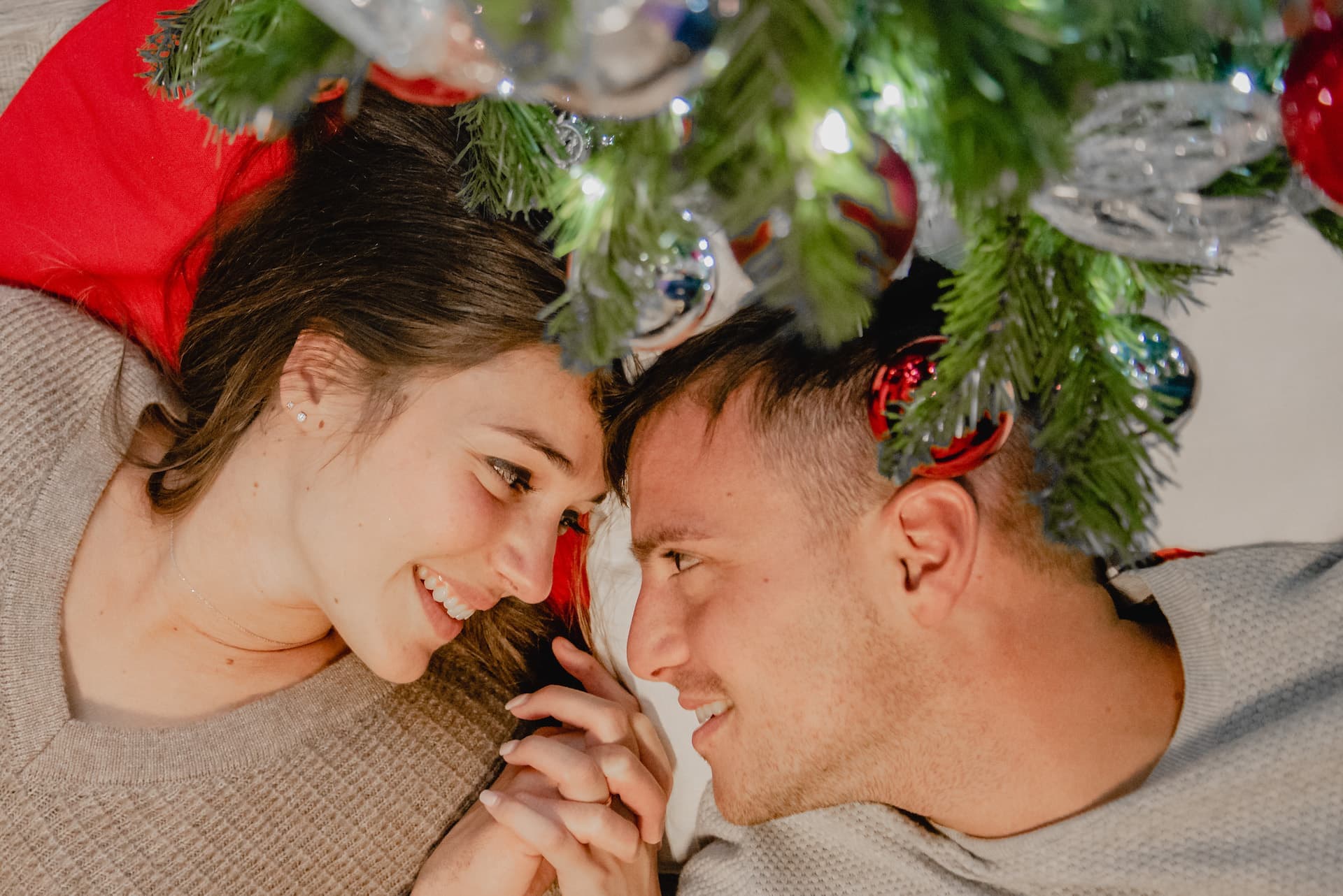 coppia a natale luci palline sotto albero sguardo