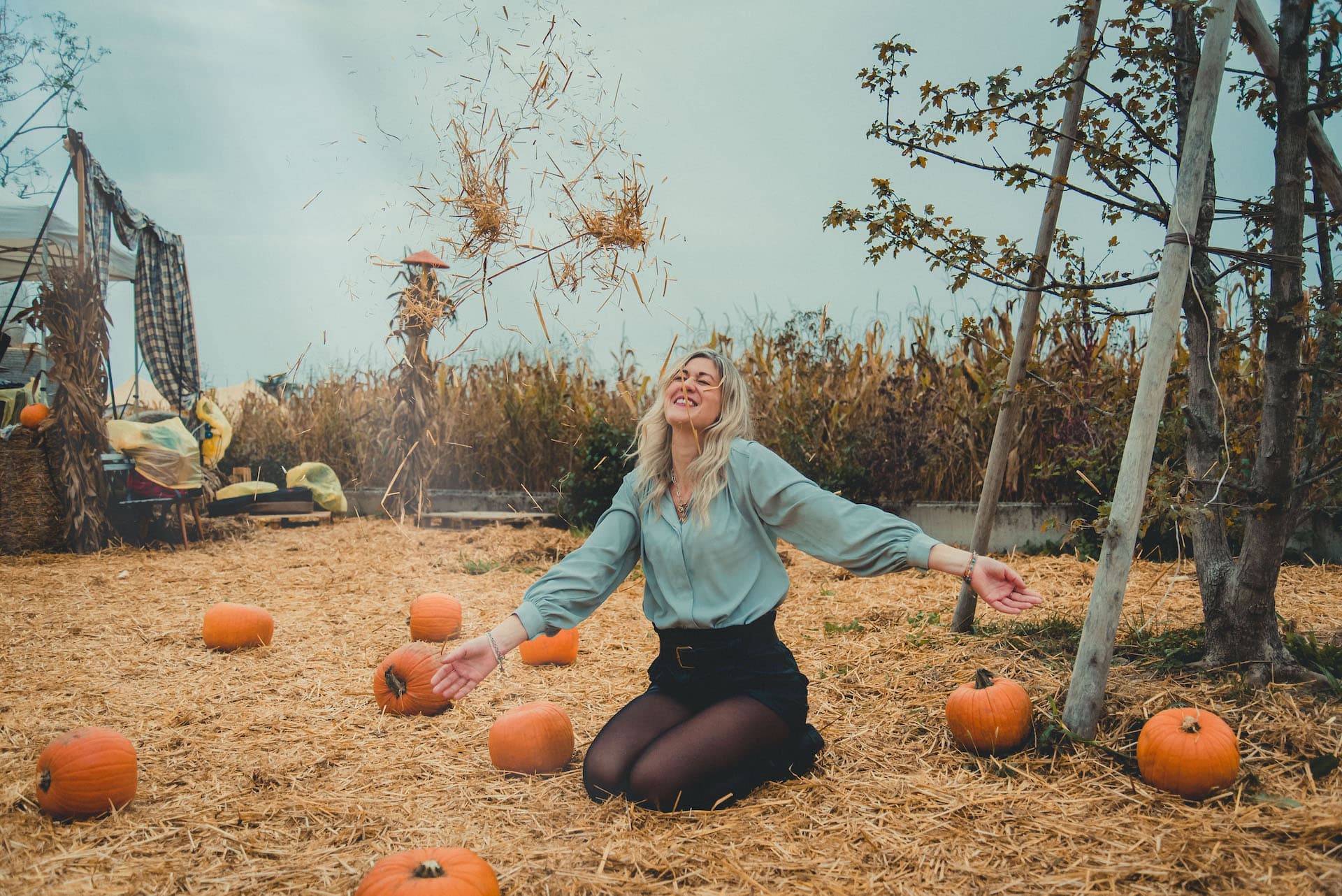 ragazza in ginocchio con zucca e fieno primo piano sorride