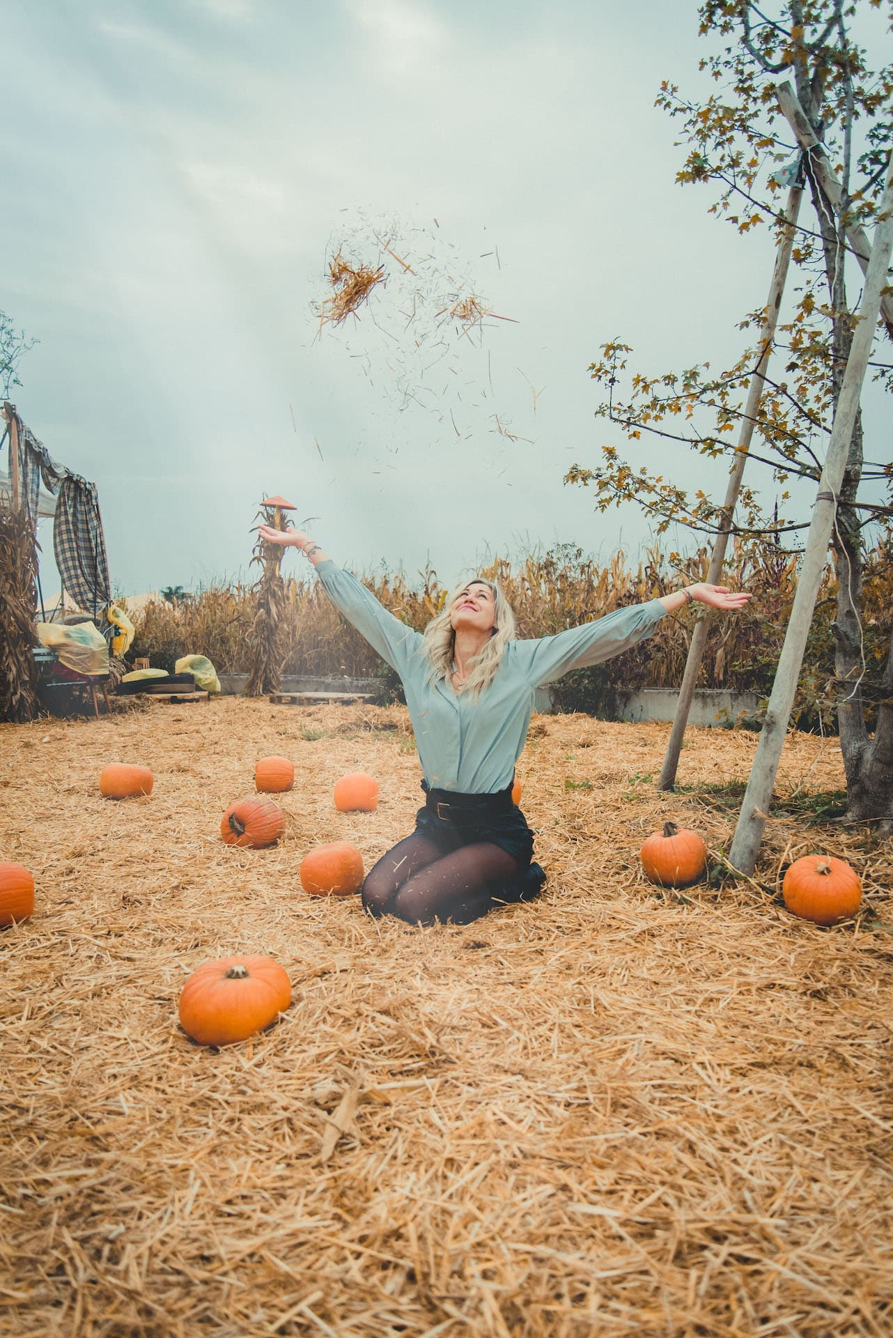 ragazza in ginocchio con zucca e fieno sorride