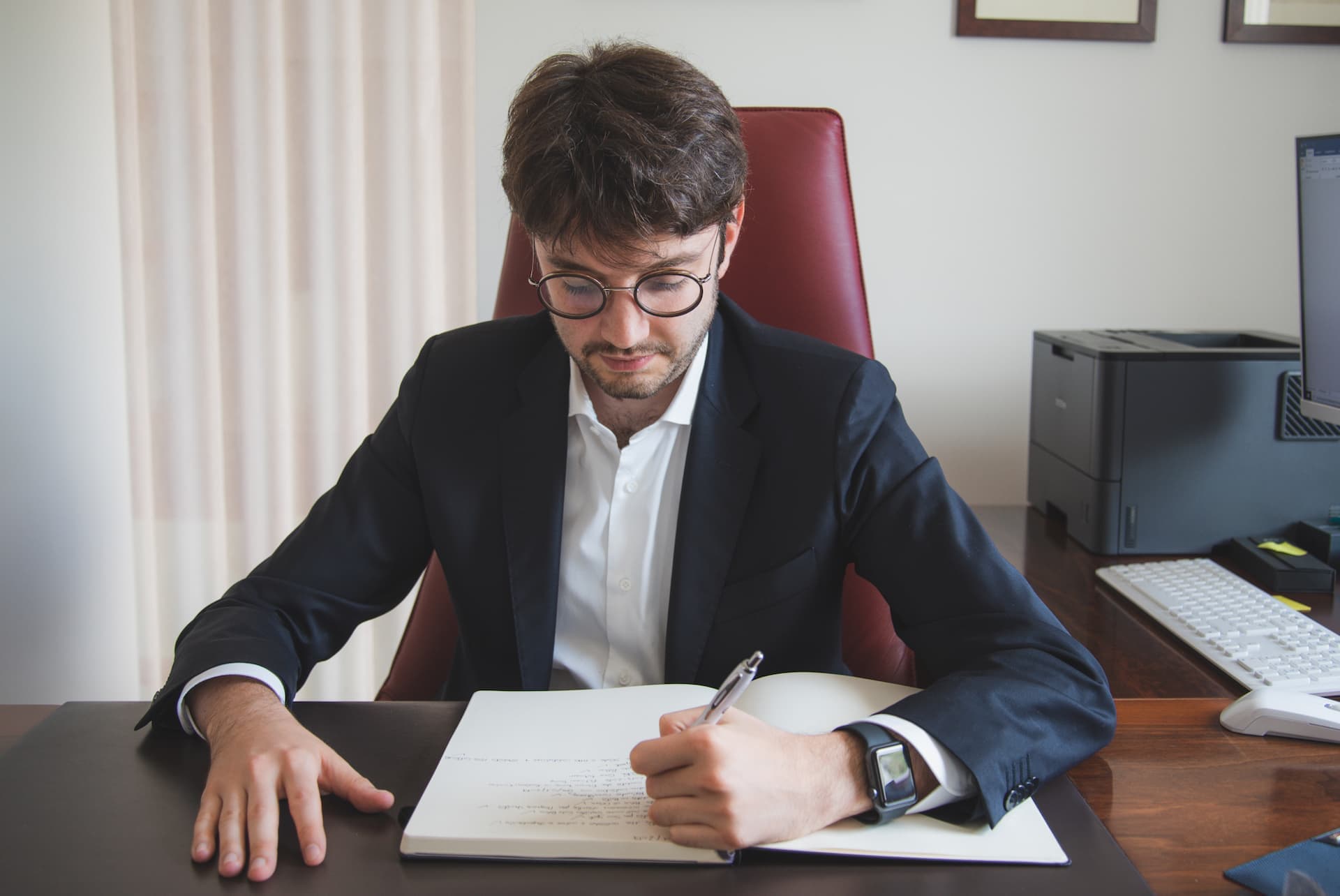 ragazzo alla scrivania con occhiali scrive