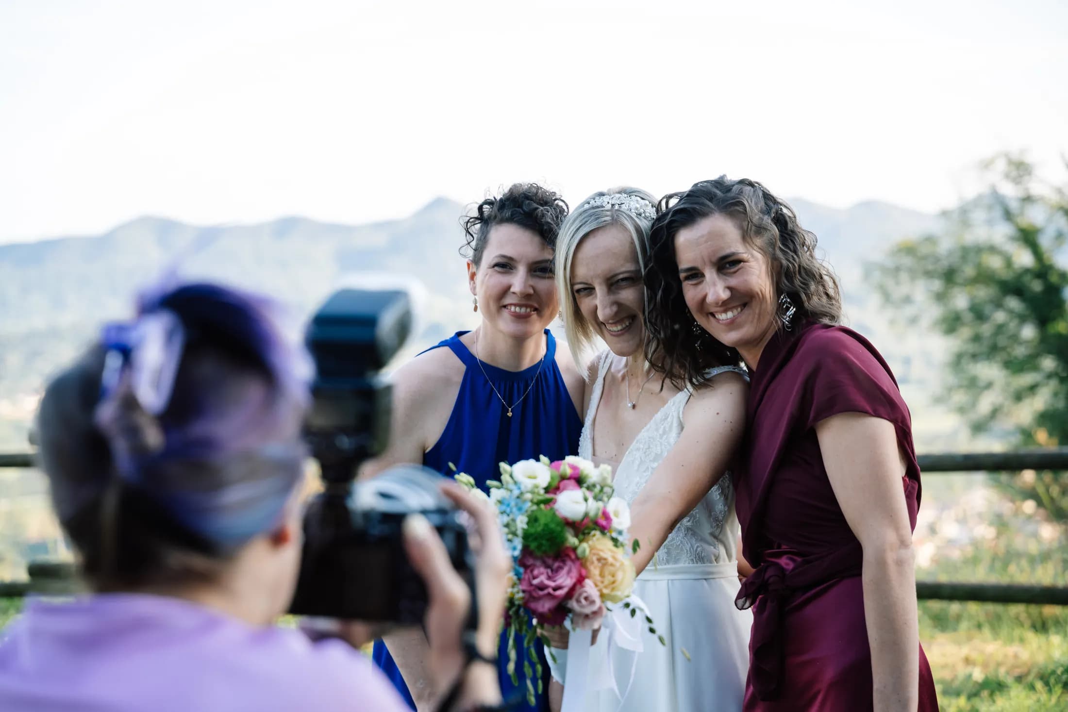 Giulia fotografa una sposa con le amiche, con le montagne sullo sfondo