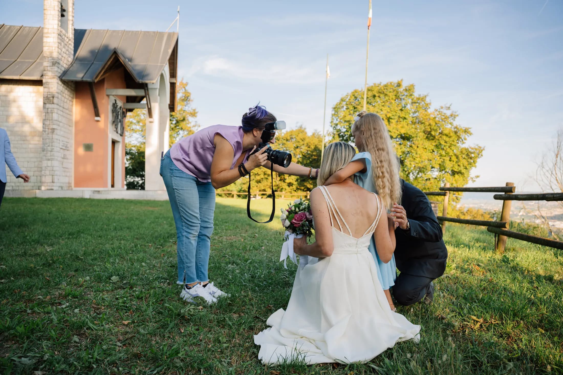 Giulia si china a fotografare una sposa seduta sul prato
