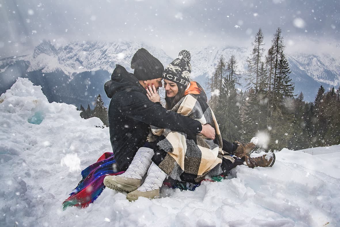 coppia neve montagna seduti abbraccio