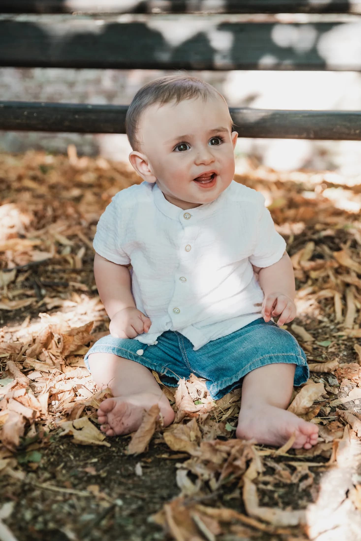 Un bambino seduto tra le foglie sorride