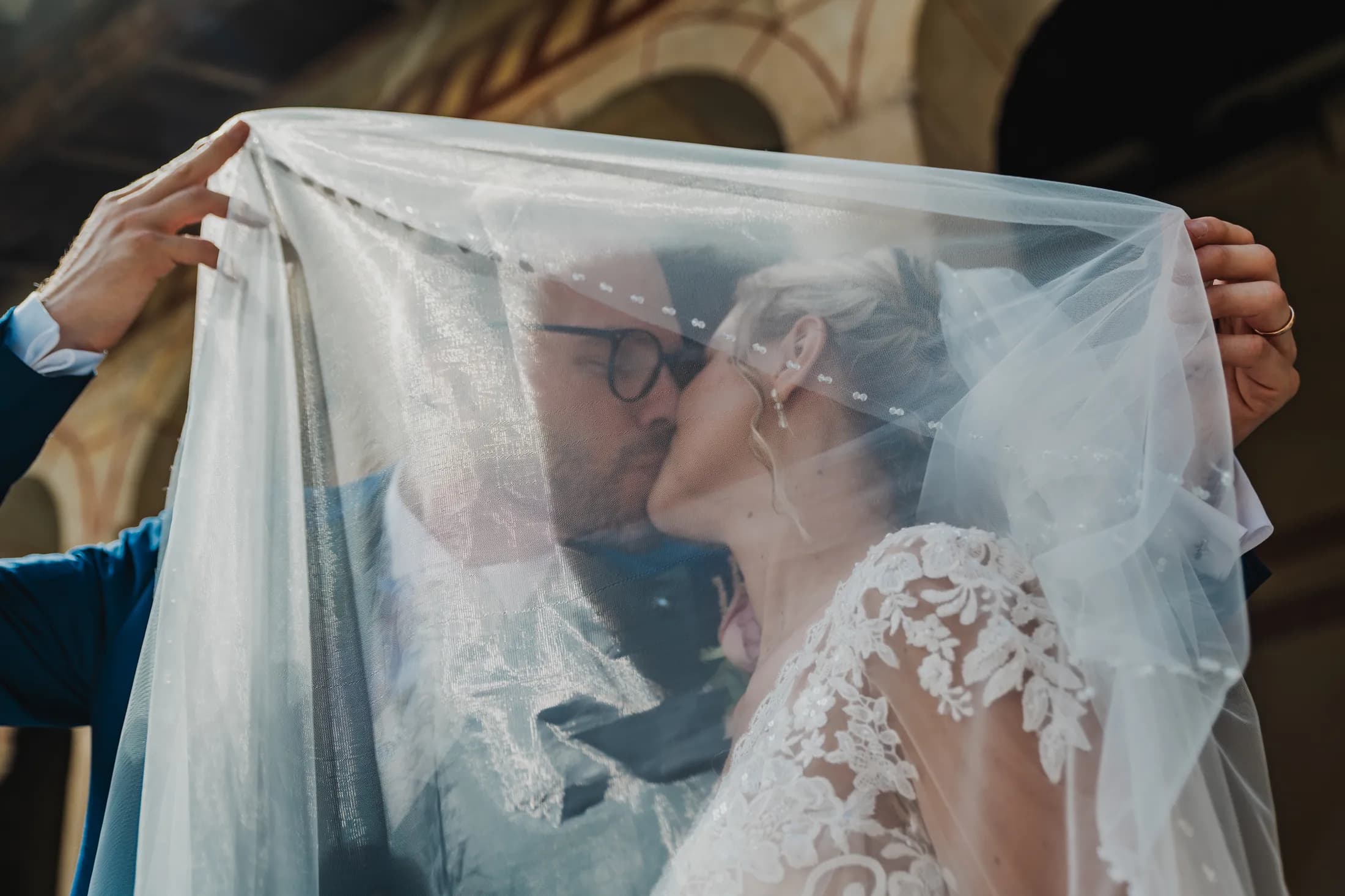 Due sposi si baciano sotto il velo della sposa