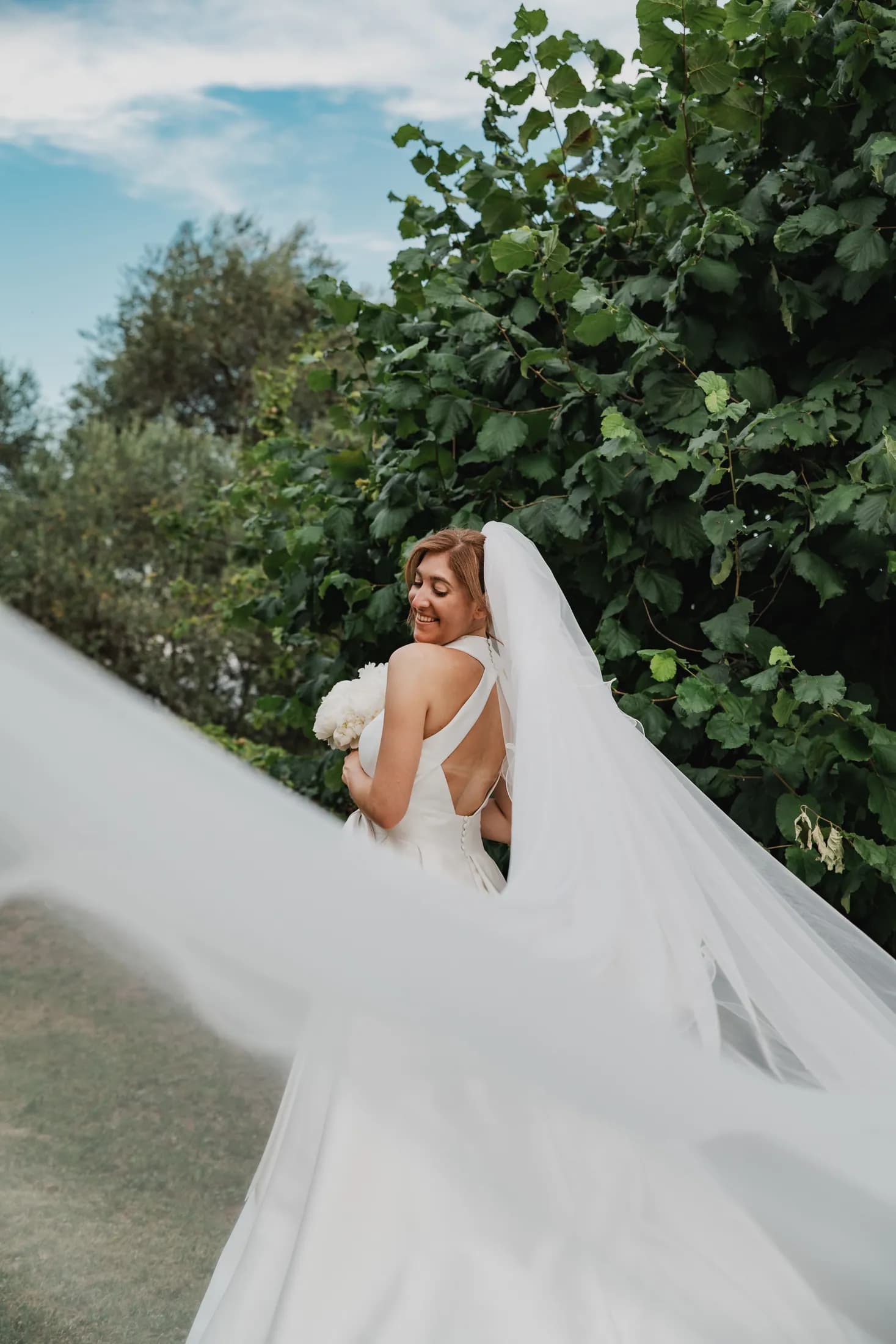 Il velo della sposa si apre nel vento in un giardino